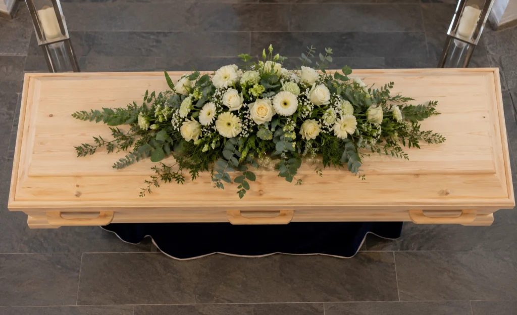 Heller Holzsarg mit weißem Blumenschmuck
