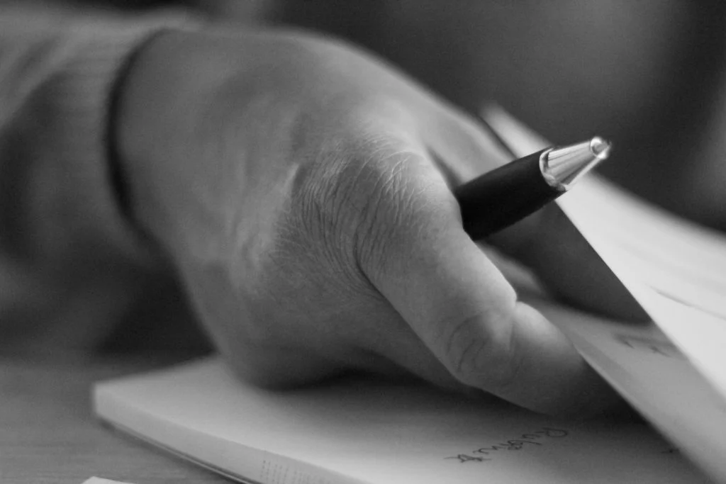 Eine Hand macht mit einem Stift Notizen auf einem Block